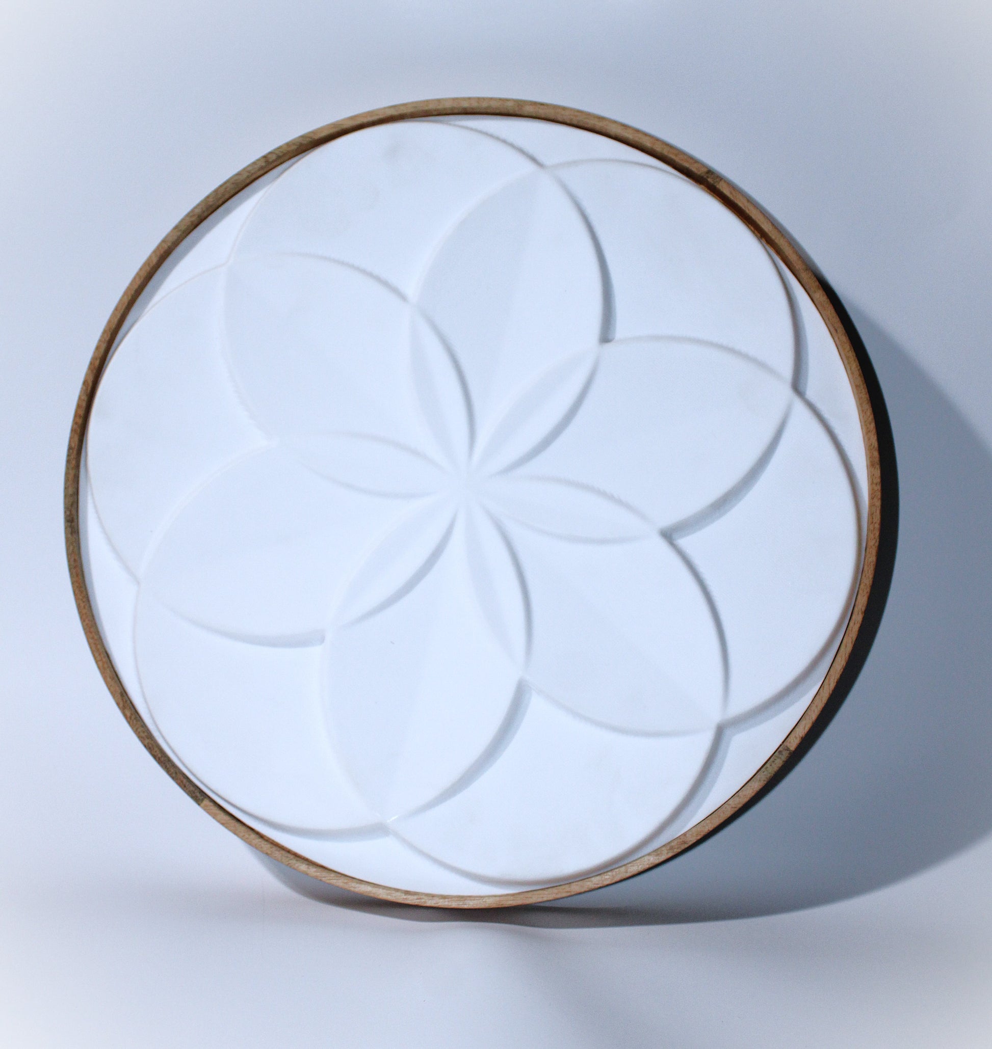 A circular wall light featuring a symmetrical floral pattern with overlapping petal-like shapes, emitting a warm, ambient glow.